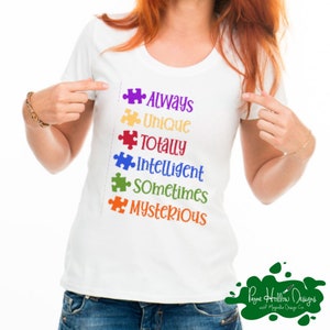 May include: A white short-sleeved t-shirt featuring a vertical list of six colorful puzzle pieces followed by the words Always, Unique, Totally, Intelligent, Sometimes, and Mysterious in matching purple, yellow, red, blue, green, and orange text.