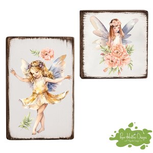 May include: Two rectangular wooden signs with distressed dark edges. One vertical sign features a blonde fairy in a yellow dress with blue wings and a pink flower. The square sign shows a fairy with brown hair, wings, and a large bouquet of pink flowers.