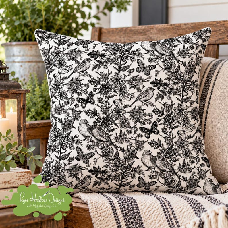 K&ouml;nnte beinhalten: Ein quadratisches Zierkissen mit einem schwarz-wei&szlig;en Toile-Muster. Das Design zeigt eine dichte Anordnung detaillierter Illustrationen verschiedener V&ouml;gel, die zwischen bl&uuml;henden Blumen, Bl&auml;ttern und mehreren verstreuten Schmetterlingen sitzen.
