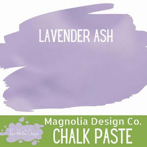 May include: A container of Magnolia Design Co. chalk paste in the color Lavender Ash. The label features a large, irregular lavender-colored brushstroke shape with the text Lavender Ash in white, and a green base with white text reading Chalk Paste.