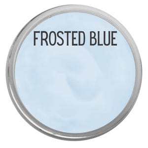 May include: A round container with a silver rim, filled with a light blue substance. The text "FROSTED BLUE" is printed in black across the center of the container. The background is white.