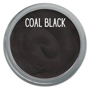 K&ouml;nnte beinhalten: Ein runder Beh&auml;lter gef&uuml;llt mit einer glatten, kohleschwarzen Substanz. Der Text COAL BLACK ist in wei&szlig;en Gro&szlig;buchstaben in der oberen Mitte des dunklen Materials aufgedruckt, das eine dicke, cremige und gleichm&auml;&szlig;ige Konsistenz aufweist.