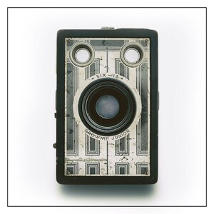 May include: A vintage black and silver Brownie Junior camera with a lens and two viewfinders. The camera has the text "SIX-16" and "BROWNIE JUNIOR" printed on it.