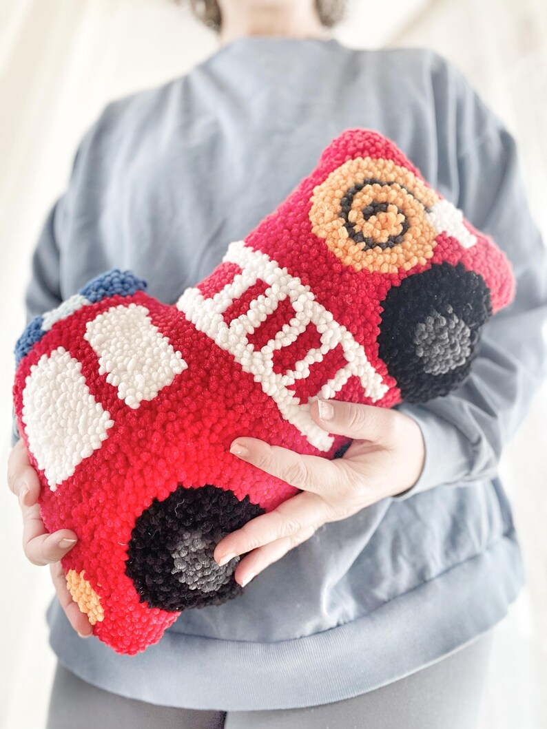 Puede incluir: Un juguete de peluche con forma de cami&oacute;n de bomberos rojo con detalles blancos y negros. El juguete est&aacute; hecho de hilo y tiene un efecto 3D.
