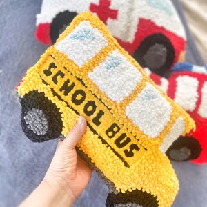 Puede incluir: Un juguete de peluche con forma de autob&uacute;s escolar amarillo con las palabras "SCHOOL BUS" en el lateral. El juguete tiene ruedas negras y ventanas blancas.