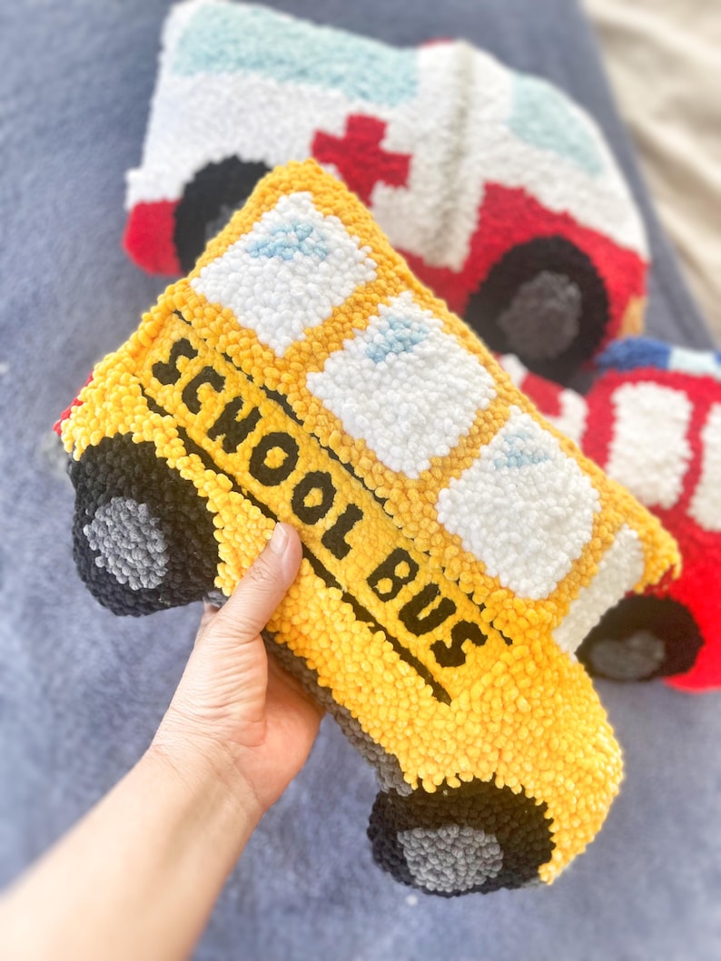 Puede incluir: Un juguete de peluche con forma de autob&uacute;s escolar amarillo con las palabras "SCHOOL BUS" en el lateral. El juguete tiene ruedas negras y ventanas blancas.