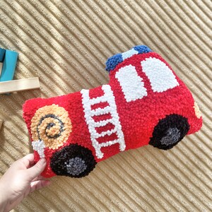 Puede incluir: Un juguete de peluche con forma de cami&oacute;n de bomberos rojo con una escalera blanca, ruedas negras y detalles amarillos. El juguete est&aacute; hecho de un material suave y peludo y es perfecto para la habitaci&oacute;n de un ni&ntilde;o.