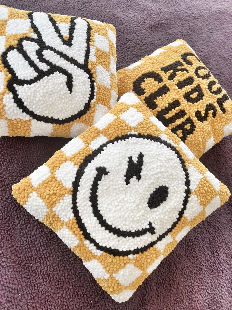 May include: Three square decorative pillows with a checkerboard pattern in yellow and white. One pillow features a peace sign, another says "Cool Kids Club", and the third has a smiley face. The designs are in black and white.