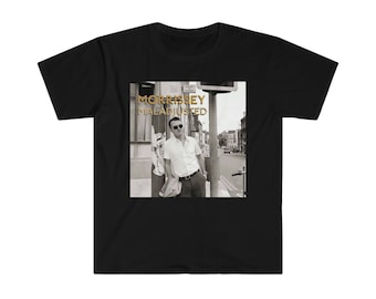 Può includere: Maglietta nera con una foto in bianco e nero di Morrissey. La foto mostra Morrissey in piedi su un angolo di strada, guardando di lato. Il testo "MORRISSEY MALADJUSTED" è stampato in oro sulla maglietta.