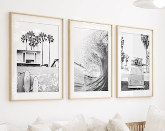 Könnte beinhalten: Drei schwarz-weiße gerahmte Fotografien einer Strandszene mit Palmen, einer brechenden Welle und einem Vintage-Van mit Surfbrettern auf dem Dach. Die Fotografien hängen an einer weißen Wand über einem weißen Sofa mit Kissen.