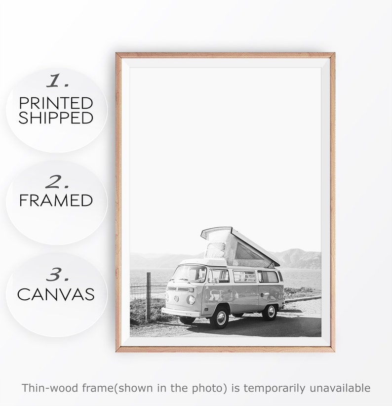 May include: Black and white photograph of a vintage camper van parked on a beach. The van has a pop-up roof and is facing the sea. The photo is framed in a thin wooden frame.