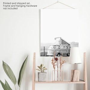 May include: Black and white photograph of a vintage camper van parked on a beach. The van has a pop-up roof and is facing the sea. The photo is printed on canvas and framed.