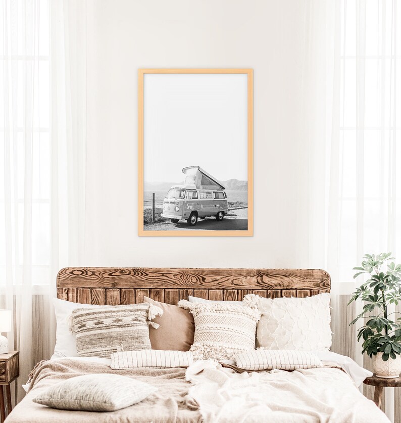 May include: Black and white photograph of a vintage camper van parked on a dirt road with a mountain range in the background.