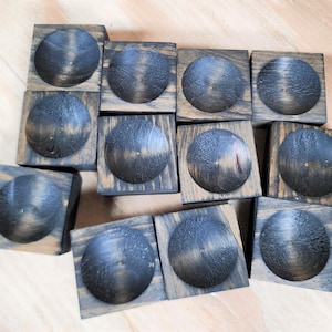 May include: A set of 12 wooden display stands with a dark brown stain. Each stand has a circular indentation in the top.