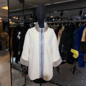 Può includere: Una giacca di pelliccia sintetica bianca con chiusura a zip e un bordo con motivo a pelle di serpente. La giacca ha un bordo in pelliccia marrone sulle maniche.