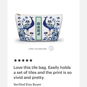 May include: White zippered pouch with a peacock design in shades of blue and green. The bag features two peacocks facing each other, with floral accents and the letters "MAHJ" in a vertical rectangle. The text "a wanda - viola original design" is at the bottom.