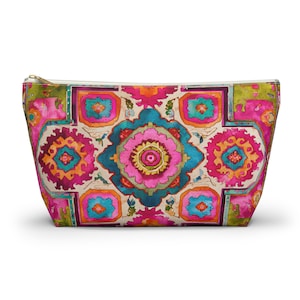 May include: A zipped pouch featuring a vibrant, symmetrical watercolour pattern in shades of hot pink, teal, lime green, and orange. The design consists of repeating geometric and floral-inspired shapes on a cream-coloured background.