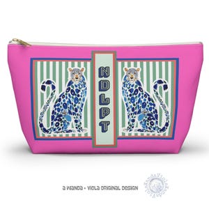 May include: A pink zippered cosmetic bag featuring a design with two blue and white leopard illustrations. The bag has a rectangular frame with green and white stripes and the letters "NDLPT".