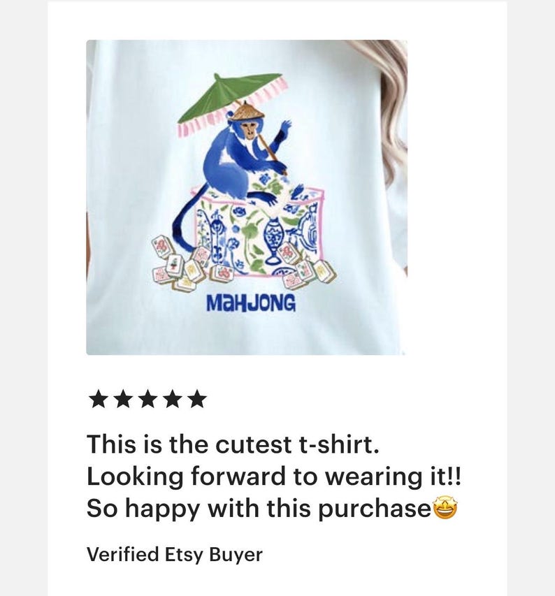 K&ouml;nnte beinhalten: Wei&szlig;es T-Shirt mit einem blauen Affen-Design, der einen gr&uuml;nen Sonnenschirm h&auml;lt, umgeben von Mahjong-Steinen. Das Wort "MAHJONG" ist blau gedruckt. Das T-Shirt ist hellblau.