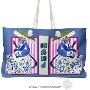 May include: Blue tote bag featuring a whimsical design with two blue monkeys wearing hats and holding parasols. The monkeys are seated on decorative containers with blue and white floral patterns. The word "MAHJ" is vertically displayed. The bag has white rope handles.