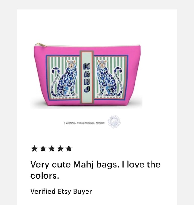 Puede incluir: Un neceser rosa con cremallera dorada, con un dise&ntilde;o de dos criaturas azules parecidas a leopardos. La bolsa tiene un panel rectangular con la palabra "MAHJ" verticalmente. El fondo tiene rayas verdes y blancas.