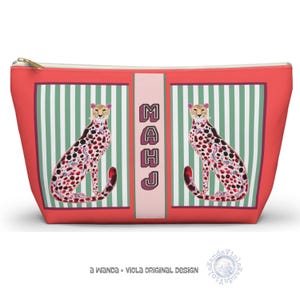 May include: A red zippered cosmetic bag with a cheetah print design. The bag features two cheetah illustrations on a green and white striped background. The word "MAHJ" is vertically printed in the center. The bag is a Wanda + Viola original design.
