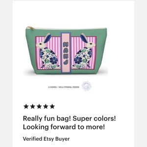 May include: A teal cosmetic bag with a gold zipper and a rectangular design featuring two white rabbits with blue ears and floral patterns. The bag has a pink and white striped background with the letters "MAHJ" in a pink rectangle.
