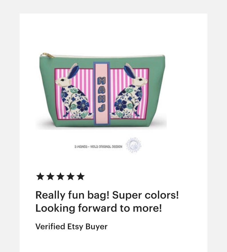 May include: A teal cosmetic bag with a gold zipper and a rectangular design featuring two white rabbits with blue ears and floral patterns. The bag has a pink and white striped background with the letters "MAHJ" in a pink rectangle.