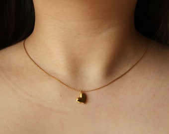 May include: A gold chain necklace with a small heart pendant.
