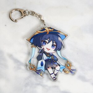 May include: A blue and gold anime character keychain with a blue hat and a white and blue scarf. The character is holding a finger to their lips and has a playful expression.