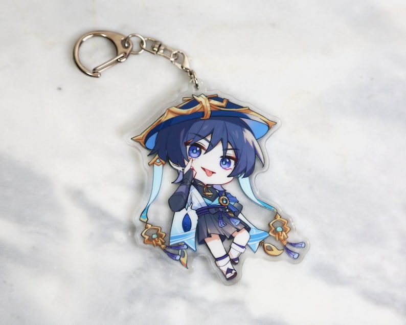 May include: A blue and gold anime character keychain with a blue hat and a white and blue scarf. The character is holding a finger to their lips and has a playful expression.