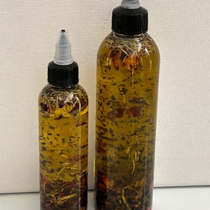 May include: Two clear glass bottles with black caps and droppers filled with a yellow liquid and dried herbs and flowers.
