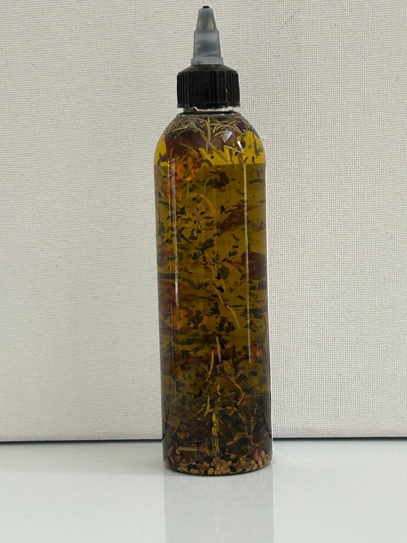 May include: A clear glass bottle with a black cap and a black dropper top. The bottle is filled with a golden liquid and contains dried herbs and flowers.