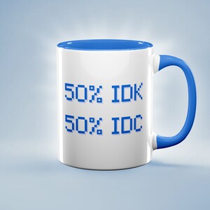 May include: White ceramic mug with a blue interior and handle. The mug features the text "50% IDK 50% IDC" in pixelated blue font. The mug is set against a light blue background.