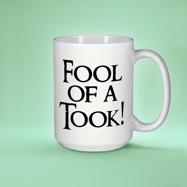 May include: White ceramic mug with a black inscription that reads "Fool of a Took!"