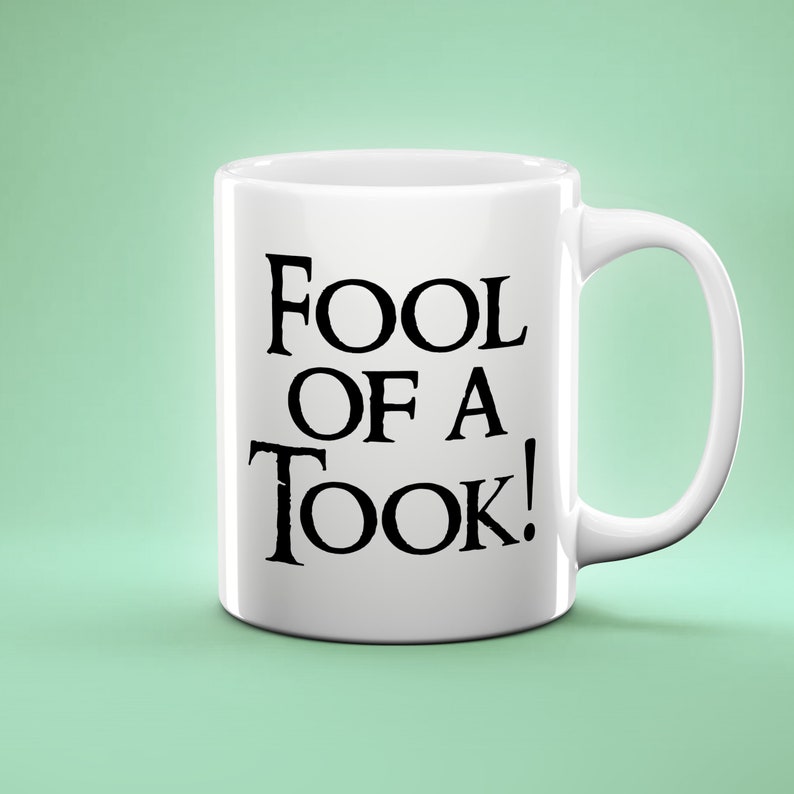 May include: White ceramic mug with black text that reads "Fool of a Took!"