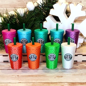 May include: Ten colorful, glittery, plastic tumblers with lids and straws. Each tumbler features the Starbucks logo and the words "Starbucks Coffee".