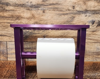 May include: Purple metal stand with a white roll of paper on a wooden surface.