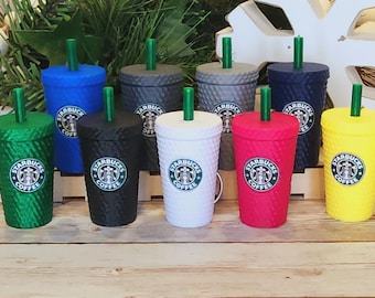 May include: Ten reusable Starbucks-style tumblers with green, blue, gray, white, red, and yellow lids and straws. The tumblers are all different colors and have the Starbucks logo on them.