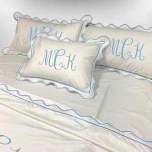 May include: White bed linens with blue scalloped trim and embroidered initials "MCK".