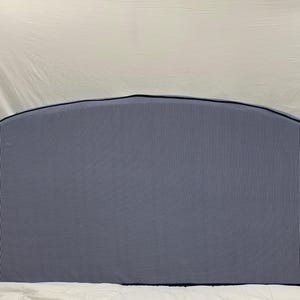 May include: A light blue headboard with a vertical striped pattern and a dark blue trim. The headboard has a rounded top and is made of a soft, textured fabric. It is designed to be placed on a bed.