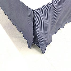 May include: A blue and white striped bed skirt with a white scalloped edge.