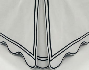May include: White fabric with a scalloped edge and black trim. The fabric has a folded design with a black border and a scalloped edge. The design is simple and elegant, suitable for home decor.