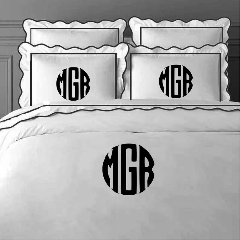 May include: White bedding with black scalloped trim and a black monogram "MGR" on each pillow and the duvet cover.
