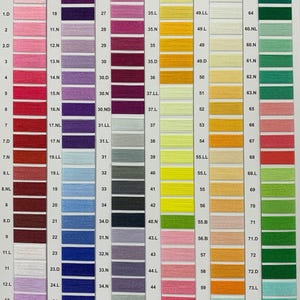 May include: A color chart of embroidery floss with numbered thread colors. The chart is divided into six strips, each with a different color range. The colors include red, pink, purple, blue, green, yellow, orange, and brown.