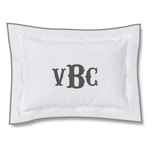 以下が含まれることがあります： グレーの縁取りが付いた白い枕。中央に濃いグレーの糸で「VBC」の文字が刺繍されている。