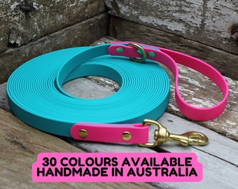 May include: A rolled turquoise dog leash with a bright pink handle and accents. The leash has a gold-colored clasp and hardware. Text on the image reads "30 COLOURS AVAILABLE HANDMADE IN AUSTRALIA."