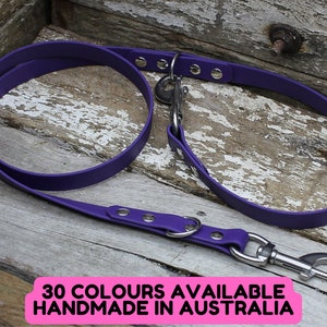 May include: A vibrant purple dog lead with a silver metal clasp and rivets. The lead is made of a flexible material and is shown on a weathered wooden surface. Text on the image reads "30 COLOURS AVAILABLE HANDMADE IN AUSTRALIA."