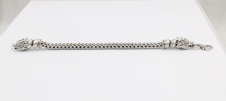 Peut inclure: Un bracelet en argent avec des fermoirs en t&ecirc;te de dragon. Le bracelet est fait d'une cha&icirc;ne tiss&eacute;e.