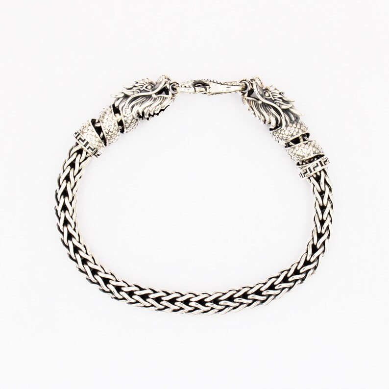 Peut inclure: Un bracelet en argent avec une cha&icirc;ne tress&eacute;e et des accents de t&ecirc;te de dragon.